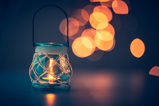 Romantic candlelight atmosphere, beautiful vintage candle lantern burning on mild blurry lights background, beauty and romance concept