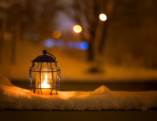 Art Christmas lantern with snowfall and lights of a winter city