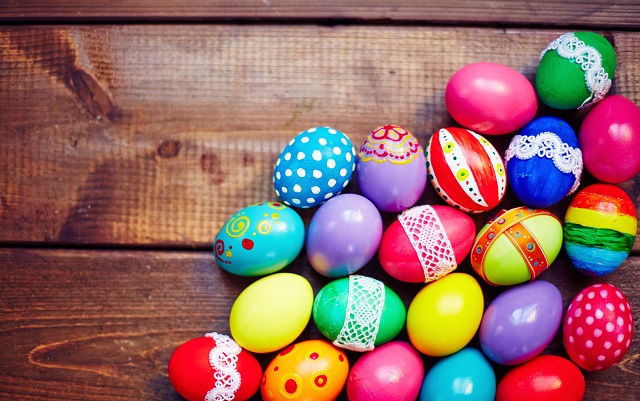 Creative Easter eggs of different colors on wooden background
